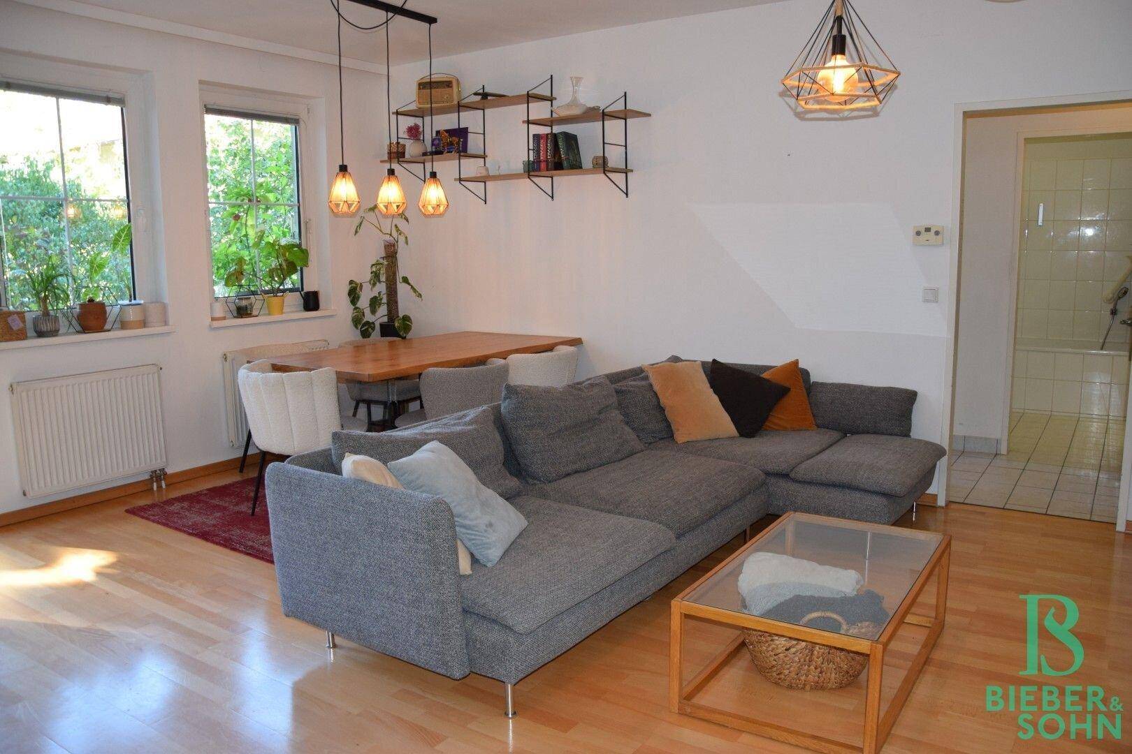 Heller Wohn-Essbereich mit Holzboden, modernem Sofa und Esstisch, ideal für gesellige Stunden.