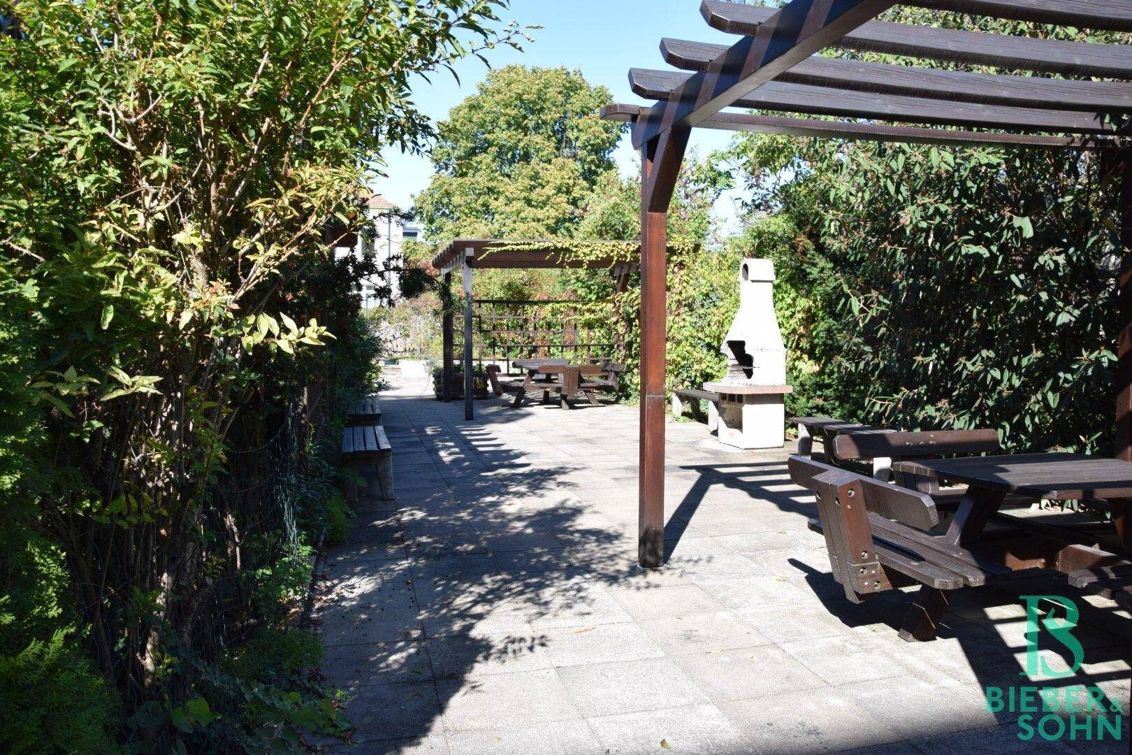 Gemeinschaftlicher Gartenbereich mit Pergolen, Picknicktischen und Grillplatz für gesellige Stunden.