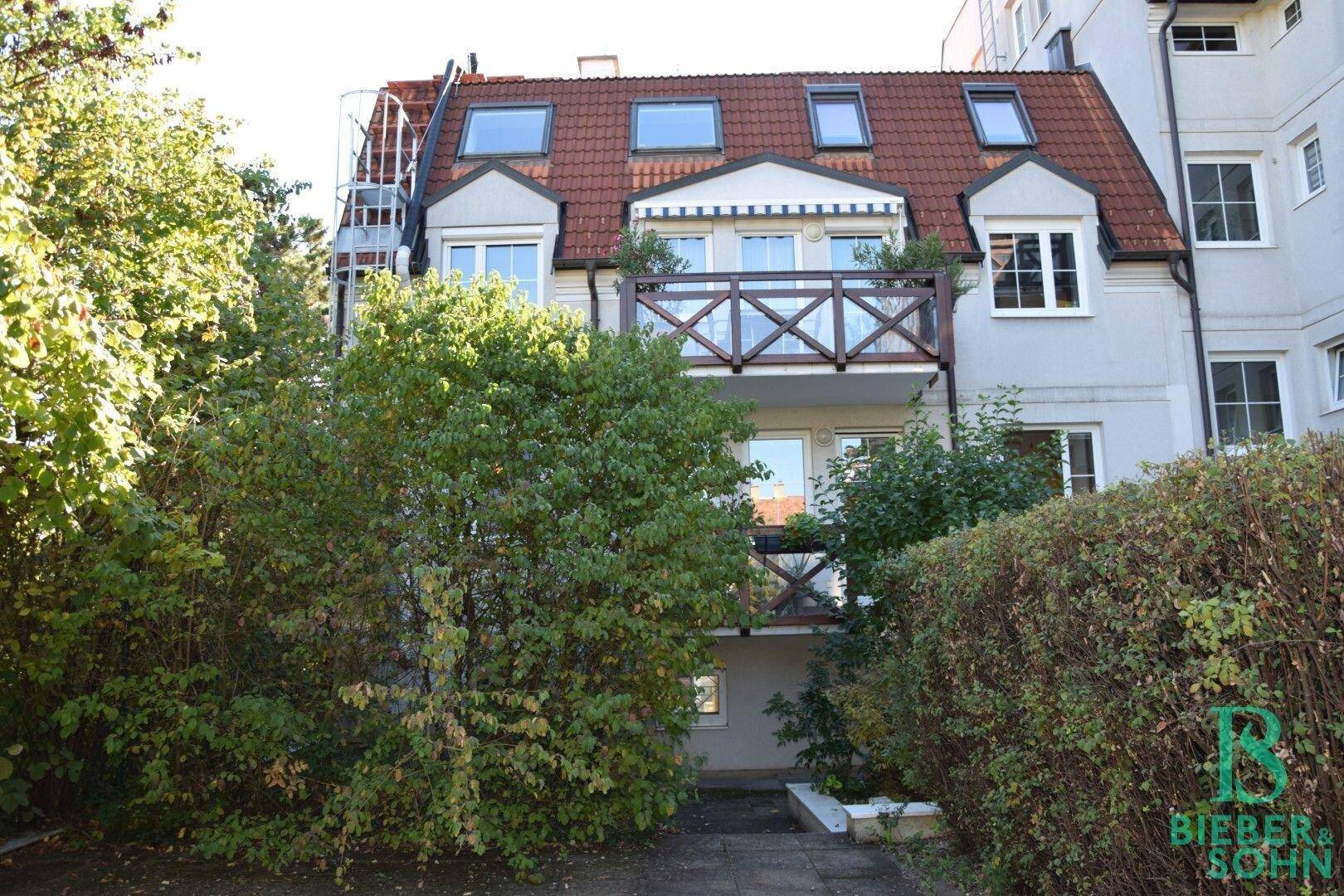 Außenansicht des Gebäudes mit mehreren Balkonen, Dachfenstern und umgebendem Grün.
