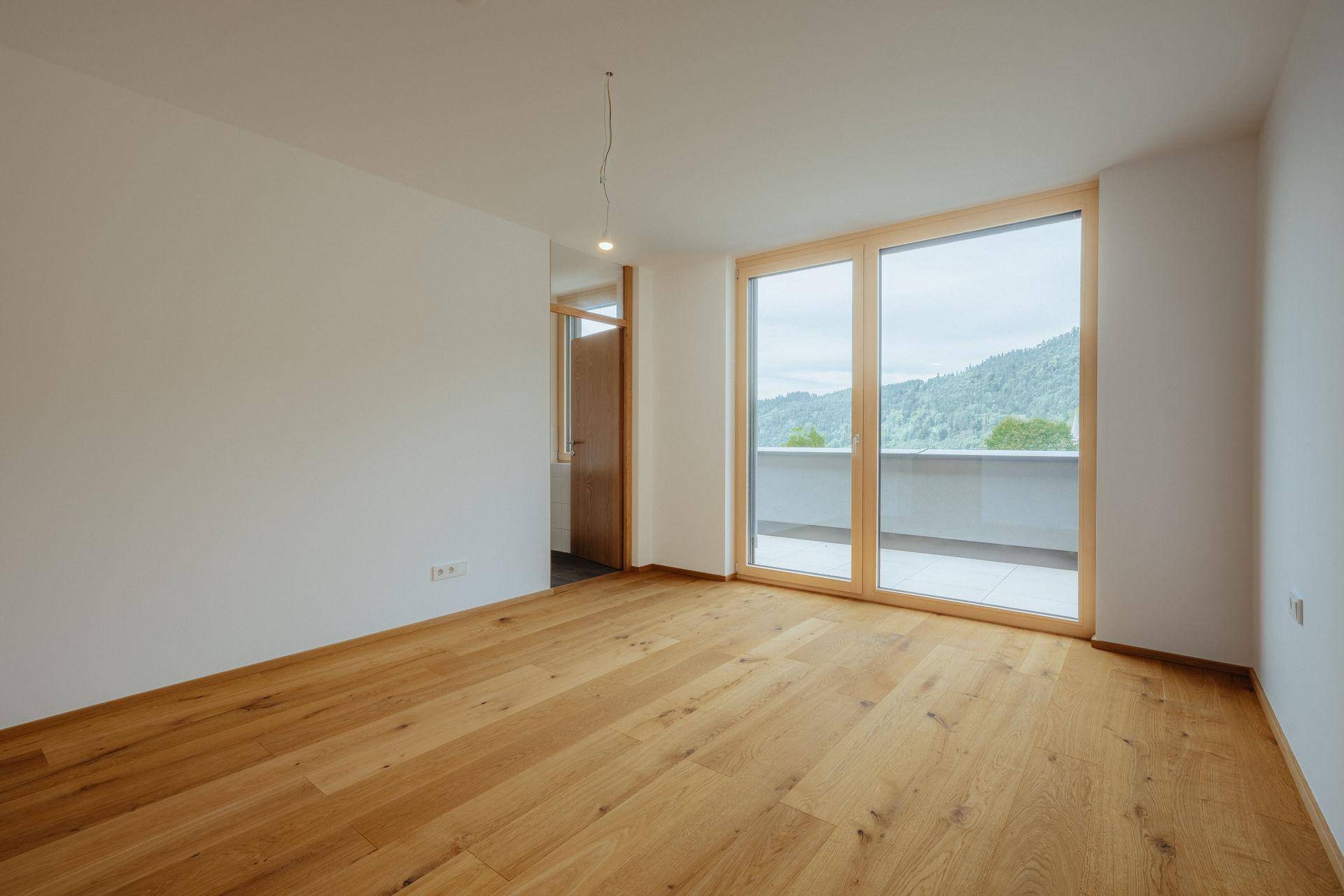 Geräumiges Schlafzimmer mit hellem Parkettboden und direktem Zugang zur Terrasse.