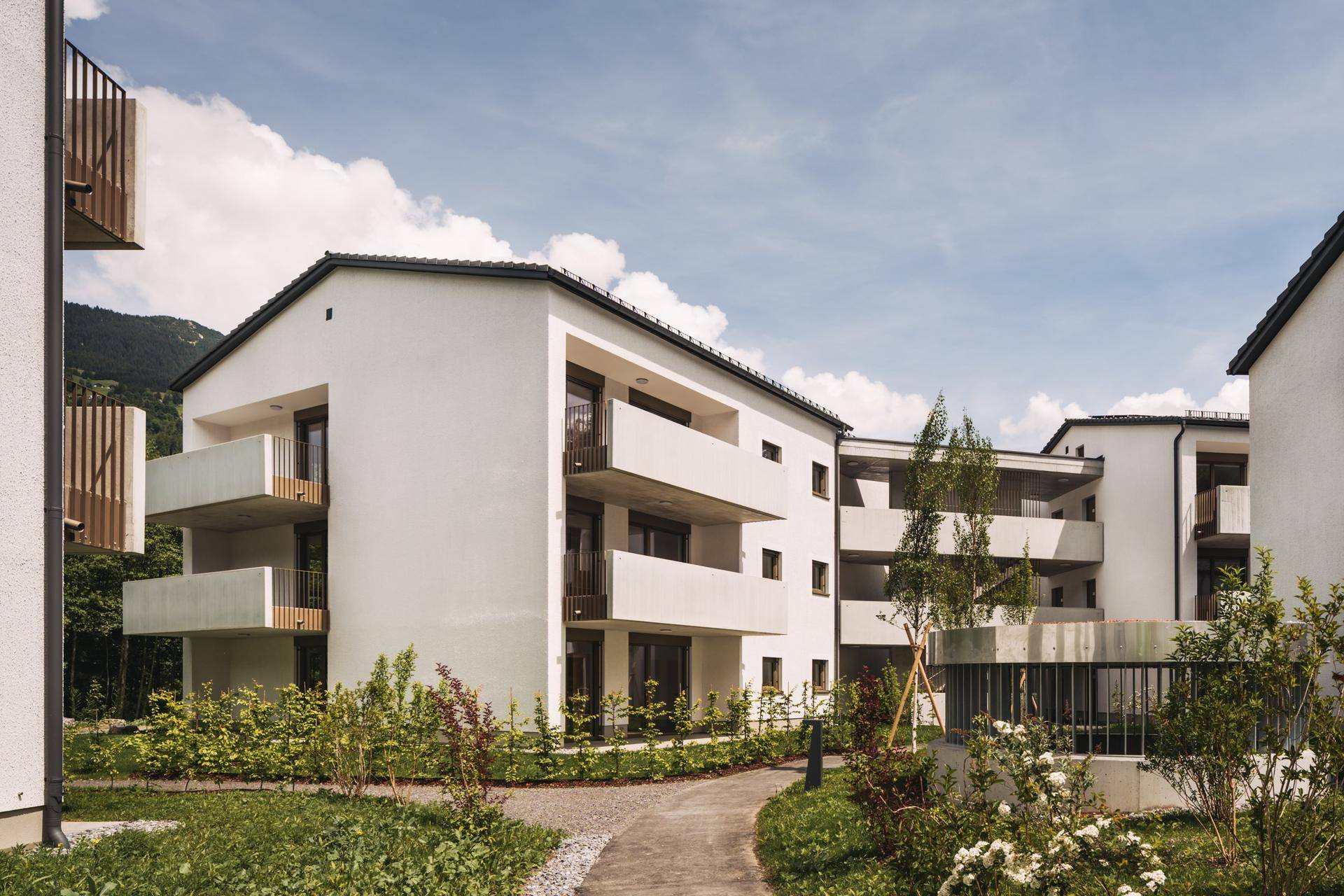 Moderne Wohngebäude mit Balkonen und gepflegten Grünflächen entlang eines Fußwegs.