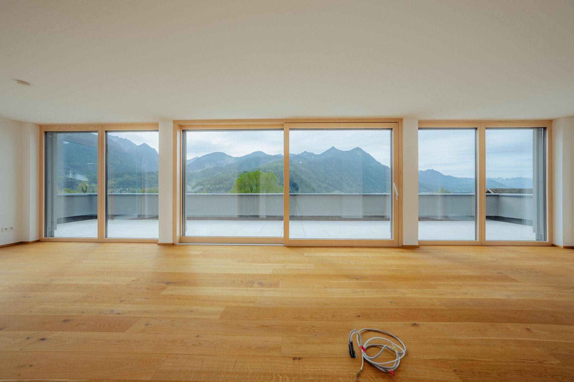 Helles Wohnzimmer mit großen Schiebetüren, Eichenparkett und beeindruckendem Bergblick.