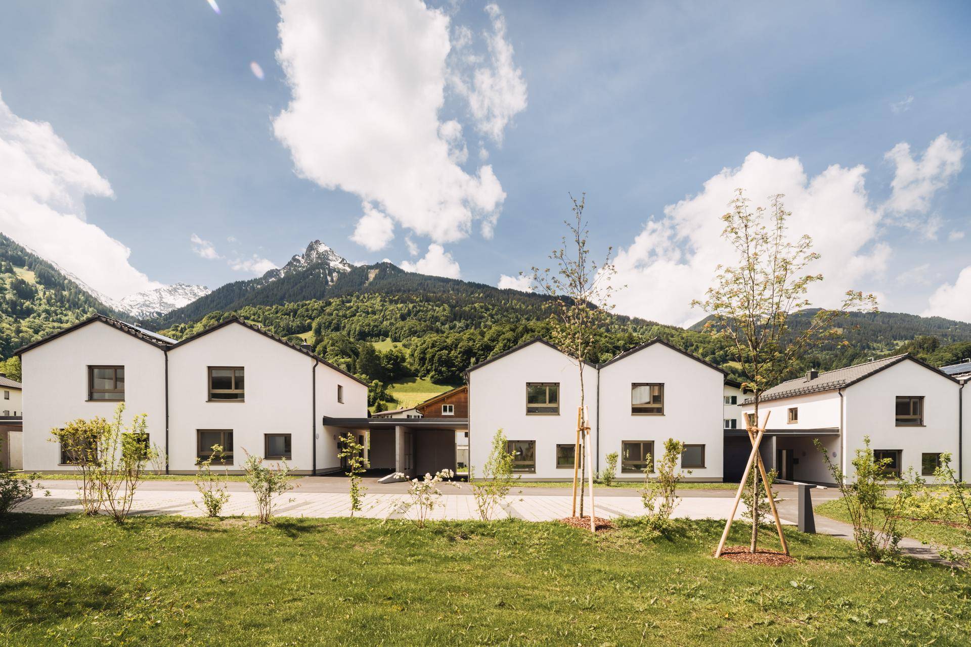 Reihe von Einfamilienhäusern mit Satteldächern und Bergblick in ländlicher Umgebung.