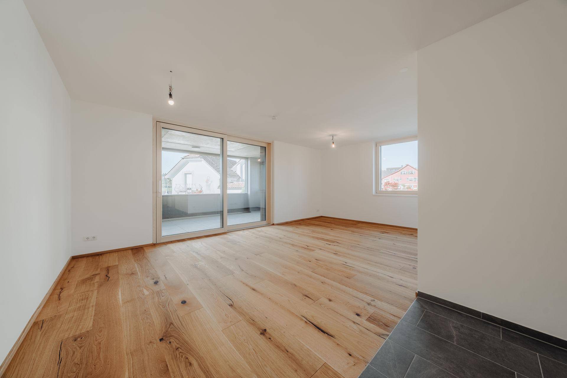 Offener Wohnbereich mit Holzboden, großen Schiebetüren und viel natürlichem Licht.