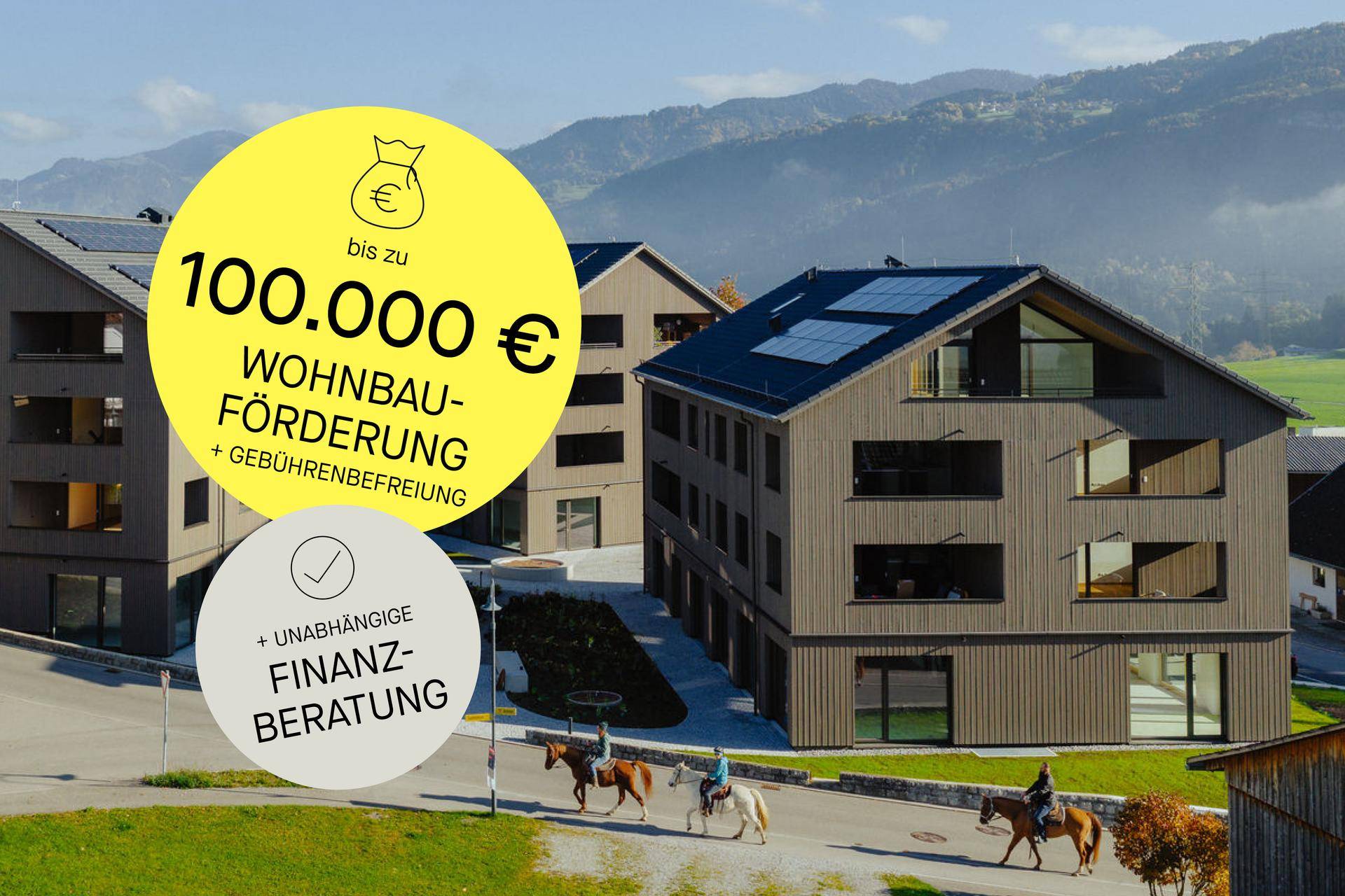 Zeitgenössische Wohngebäude mit Holzfassaden und Solaranlagen, umgeben von Natur und Bergen, mit Reitern im Vordergrund.