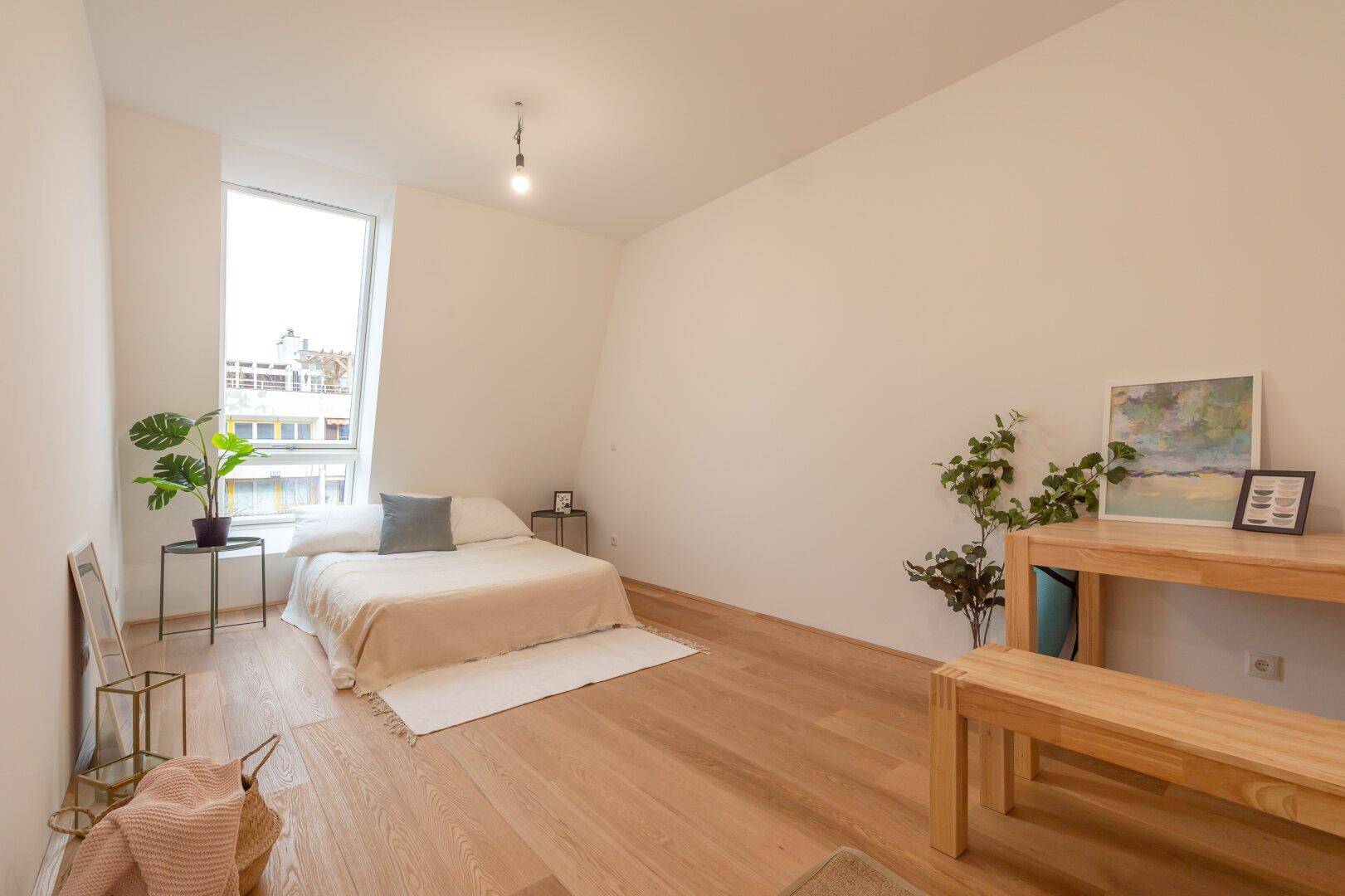 Helles Schlafzimmer mit Holzboden, großem Fenster und minimalistischer Einrichtung, mit Stadtblick.