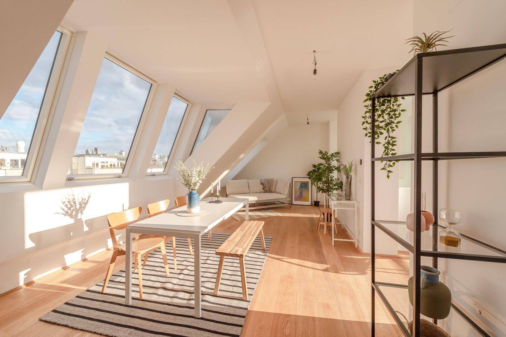 Sonniger Wohn- und Essbereich im Dachgeschoss mit Holzboden, Dachfenstern und moderner Einrichtung.