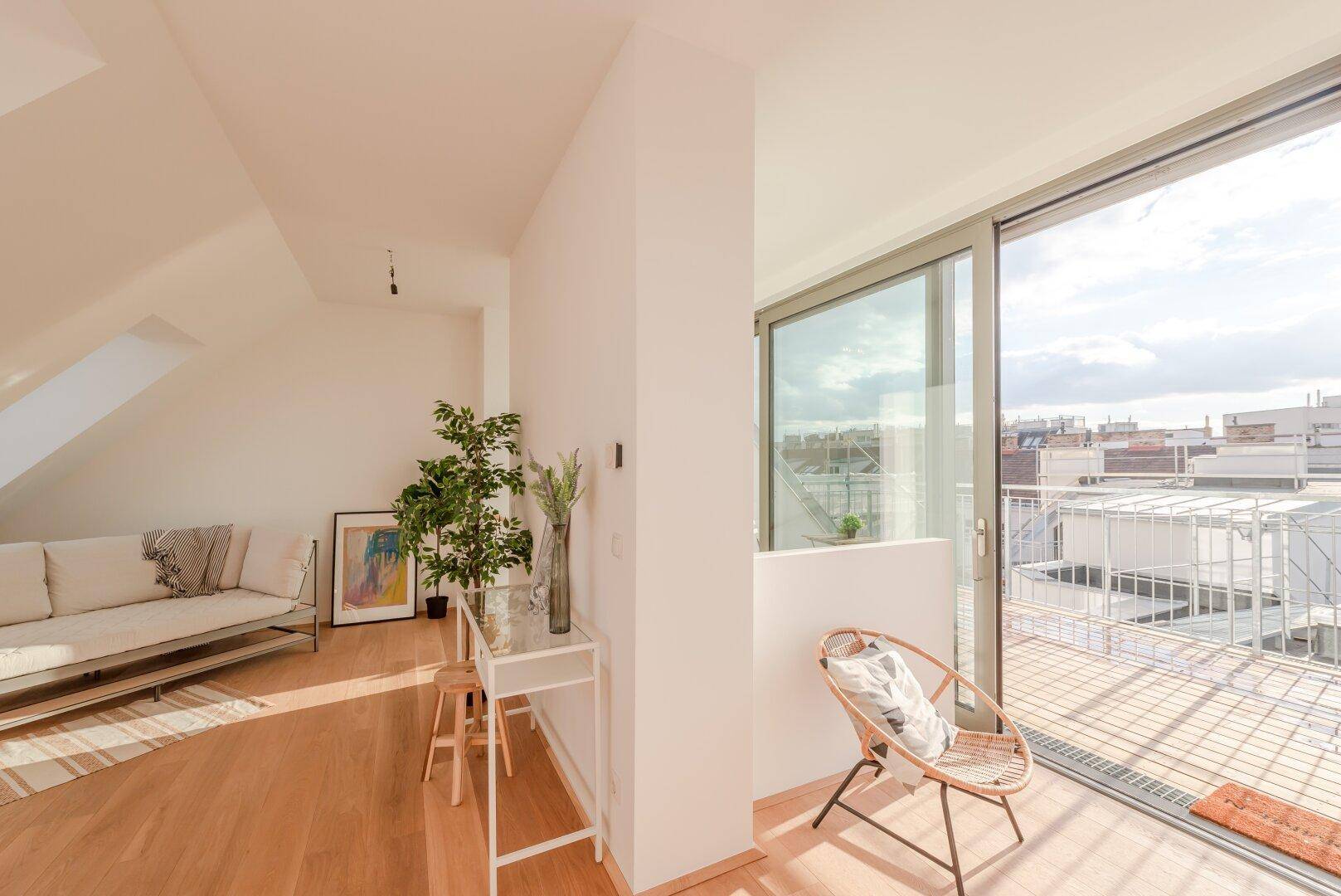 Heller Wohnbereich mit Holzboden und Schiebetür, die zu einem sonnigen Balkon führt.