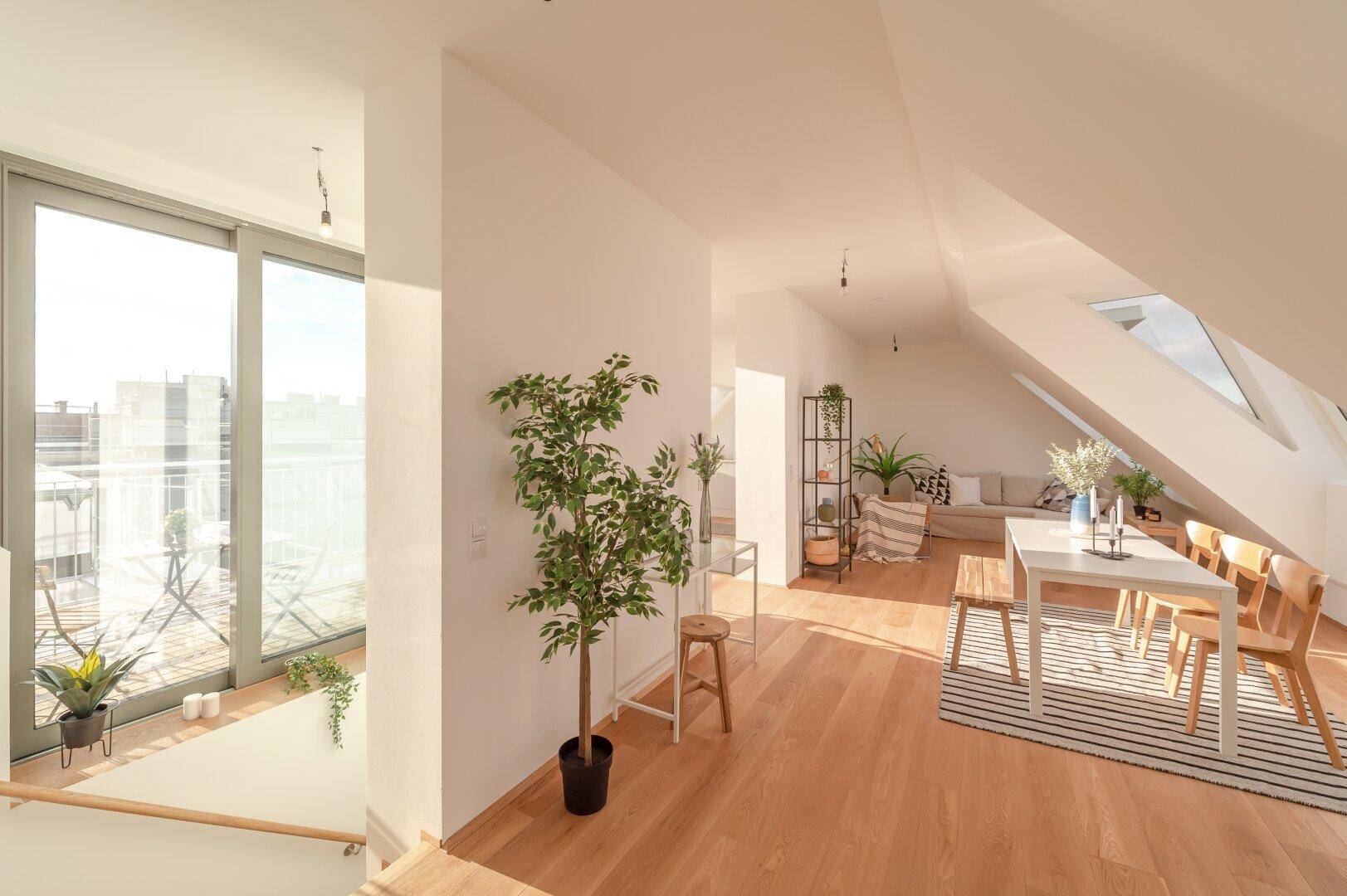 Heller Wohn- und Essbereich mit Holzboden und Zugang zu einem sonnigen Balkon, modern eingerichtet.