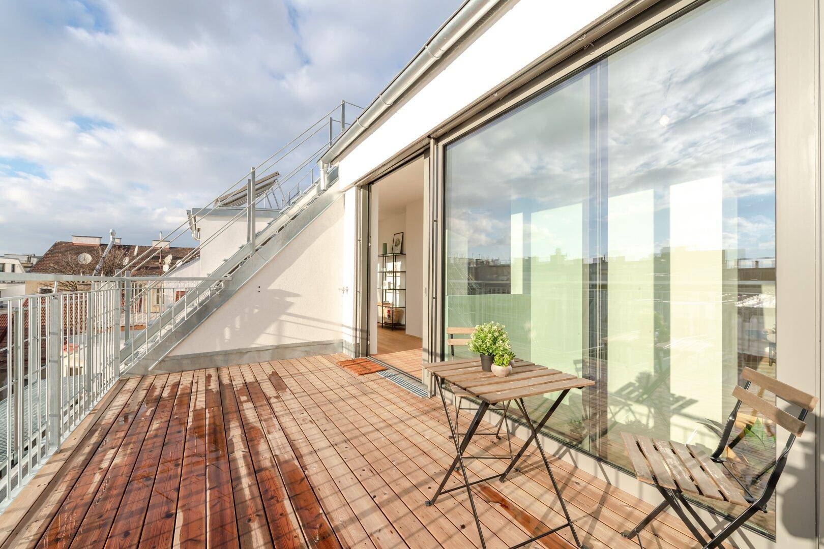 Kleiner Balkon mit Holzboden und Sitzgelegenheiten, ideal für entspannte Stunden im Freien.