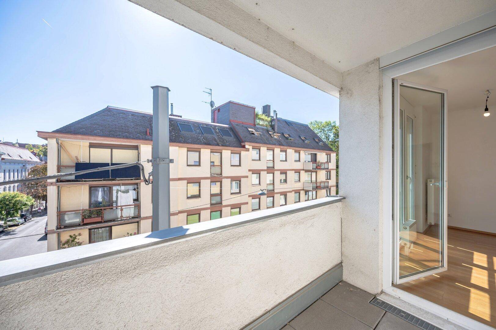 Balkon mit Weitblick über die Stadt und angrenzende Gebäude, ideal für entspannte Stunden.