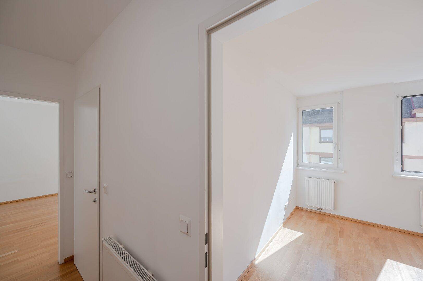 Heller Raum mit Parkettboden und Fenster, der als Schlafzimmer oder Arbeitszimmer genutzt werden kann.