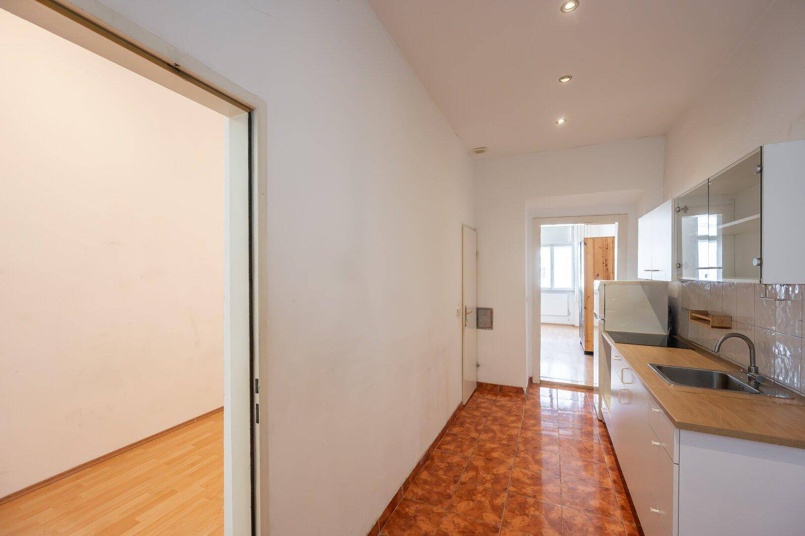 Flur mit Fliesenboden, der die Küche mit einem weiteren Zimmer verbindet.
