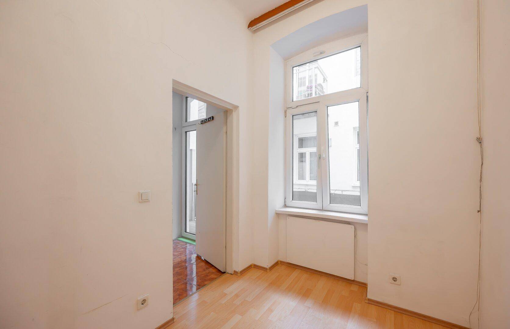 Helles Zimmer mit großem Fenster und Holzboden, ideal als Schlaf- oder Arbeitszimmer.