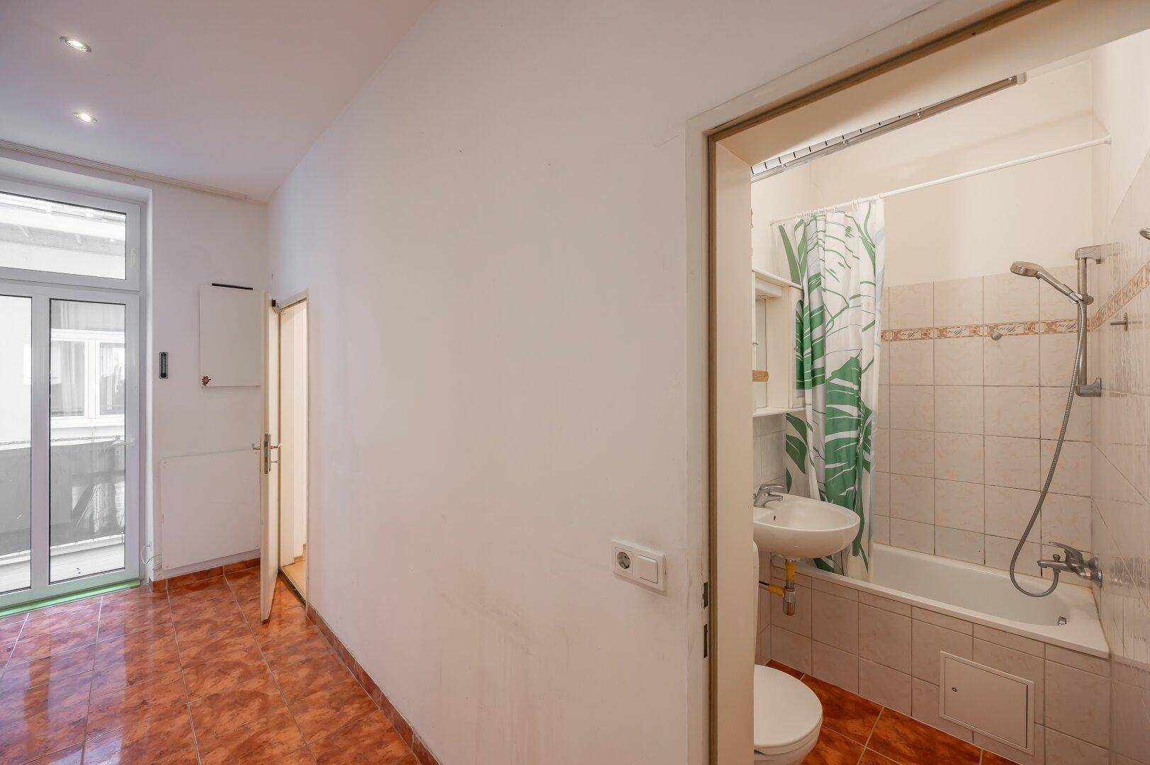 Badezimmer mit Badewanne, Waschbecken und Fliesen an Wänden und Boden.