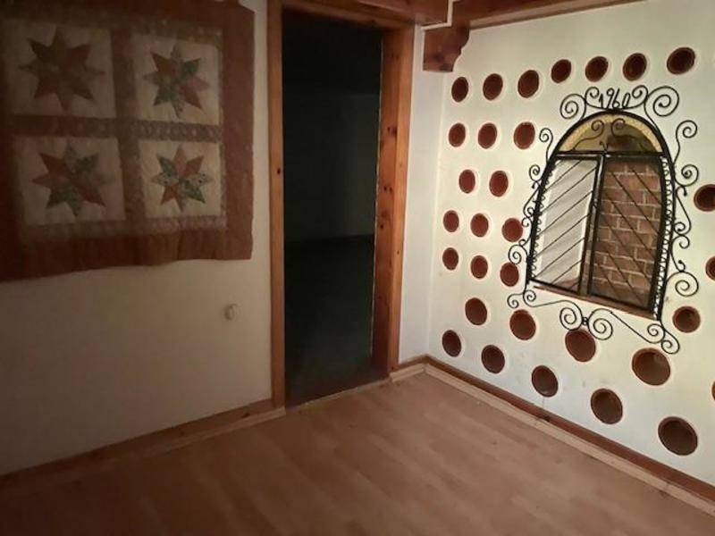 Zimmer mit Holzboden und einer kreativ gestalteten Wand mit runden Aussparungen.
