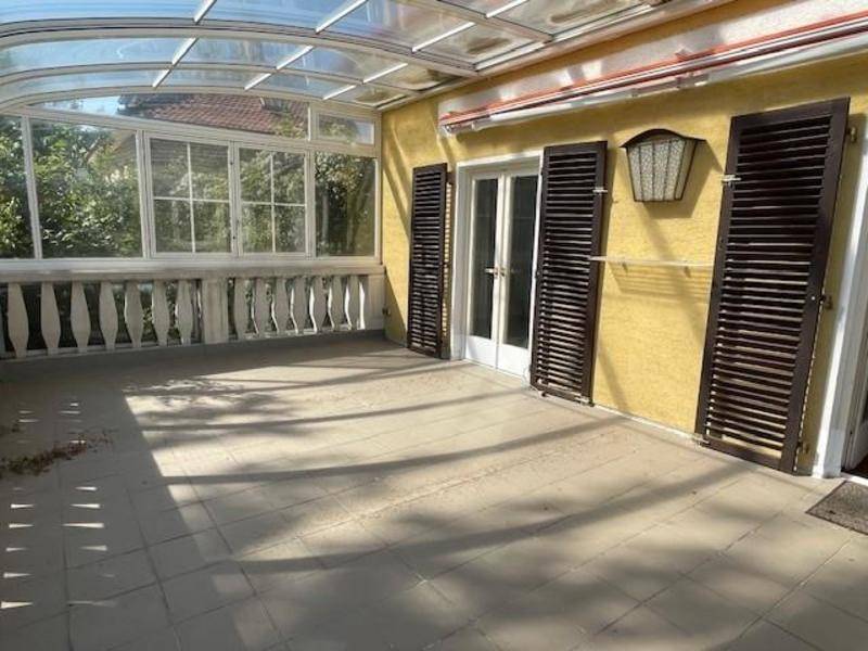 Große geflieste Terrasse mit Glasdach und Blick ins Grüne, ideal für den Außenbereich.