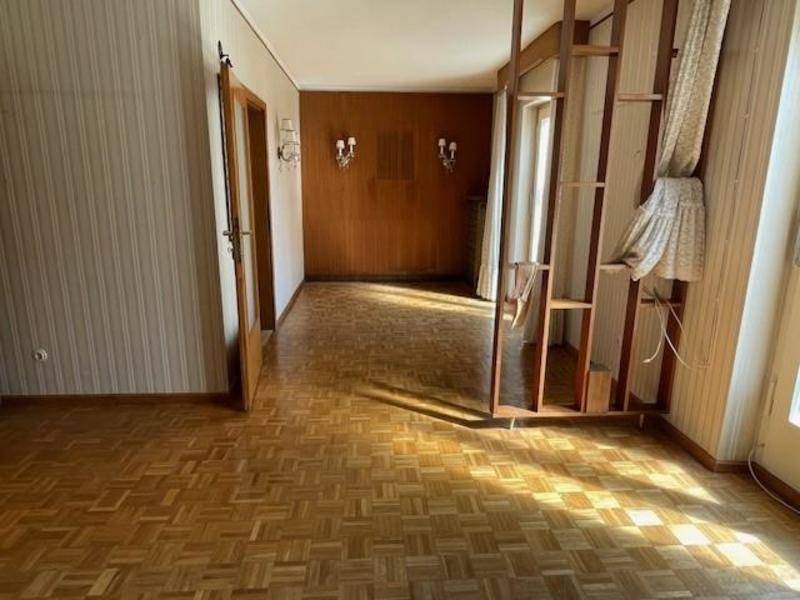 Heller Wohnbereich mit Parkettboden, Holzwänden und einem dekorativen Raumteiler.