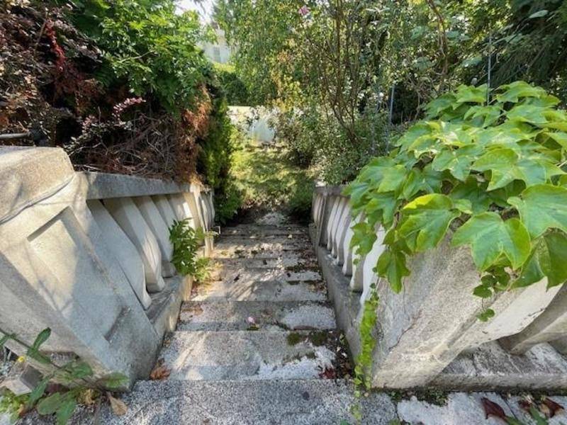 Alte, von Pflanzen überwucherte Steintreppe mit dekorativen Balustraden in einem Garten.