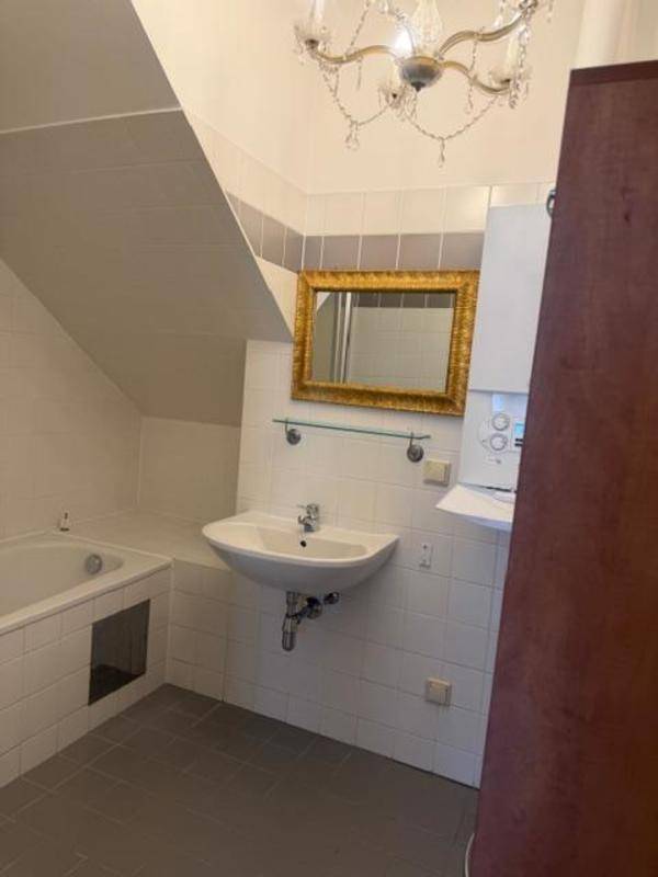 Badezimmer im Dachgeschoss mit Badewanne, Waschbecken und schrägen Wänden.