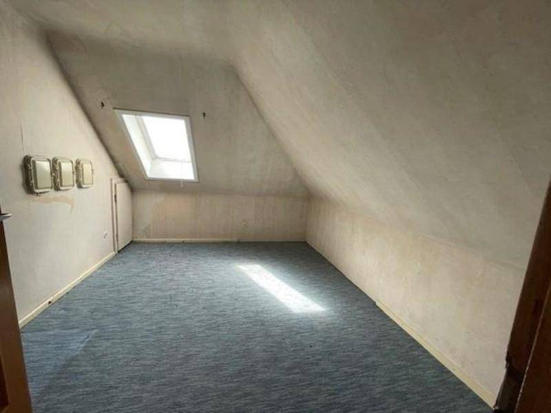 Dachzimmer mit Teppichboden, Dachschräge und einem Dachfenster für natürliches Licht.