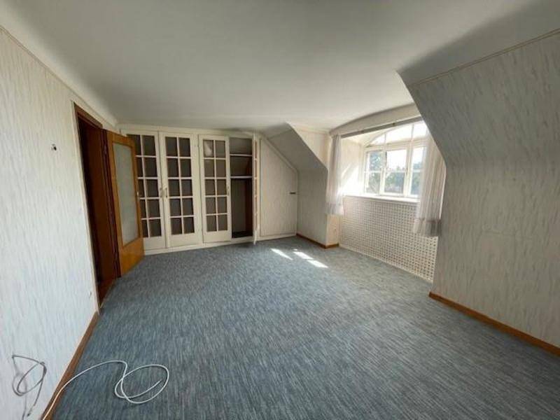 Schlafzimmer mit Teppichboden, Dachschräge und Einbauschränken unter dem Fenster.