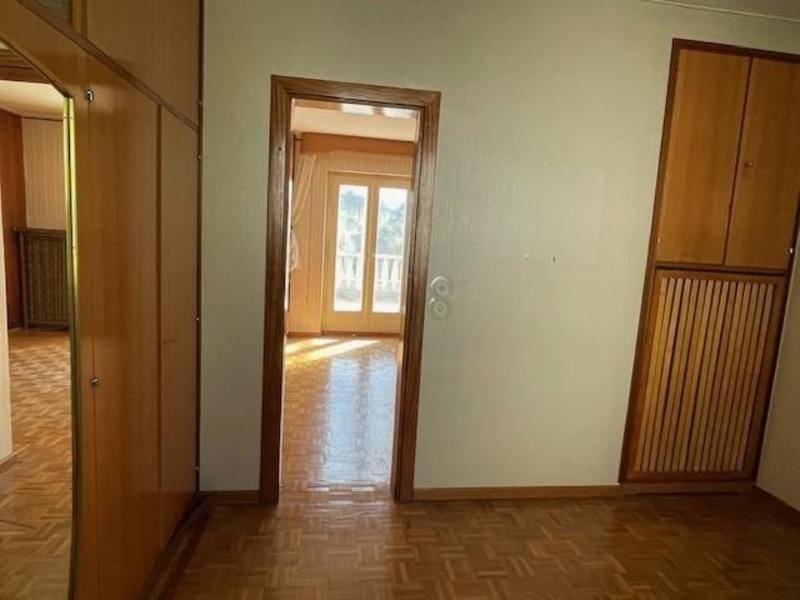 Zimmer mit Parkettboden und Einbauschränken, das zu einem weiteren Raum führt.