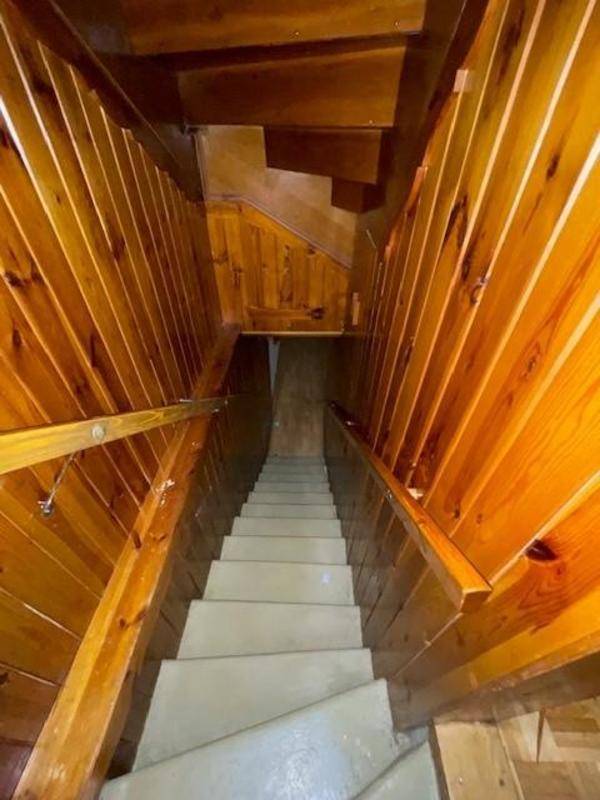 Rustikale Holztreppe, die in den Kellerbereich führt, umgeben von Holzvertäfelung.