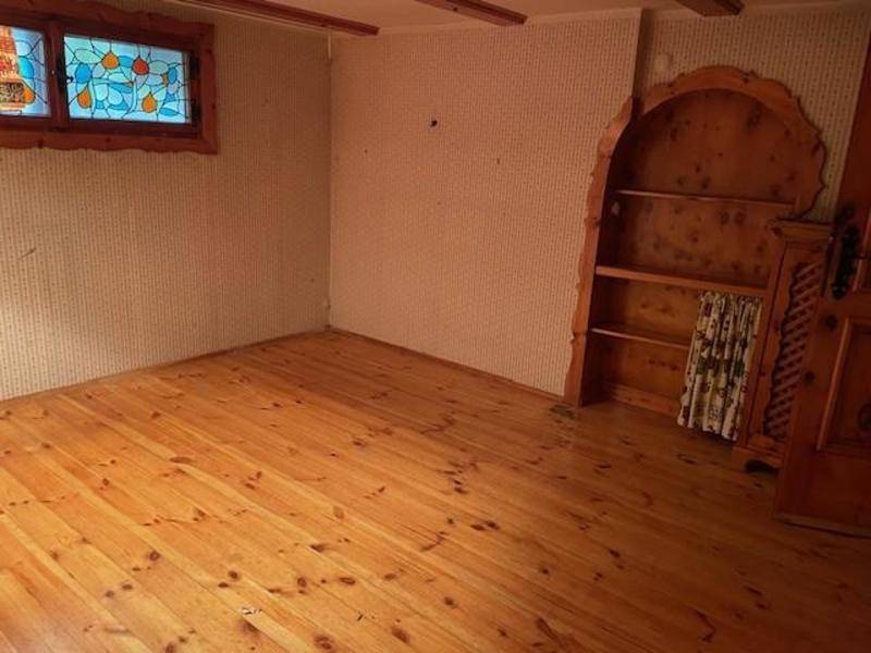 Zimmer mit Holzdielenboden, Einbauregal und einem farbenfrohen Buntglasfenster.