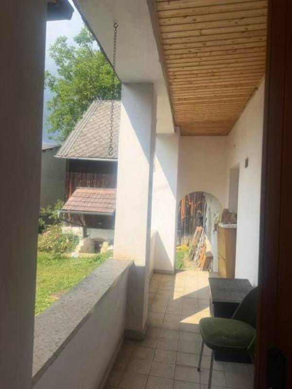 Überdachte Loggia mit Fliesenboden und Blick auf den Garten und Nebengebäude.