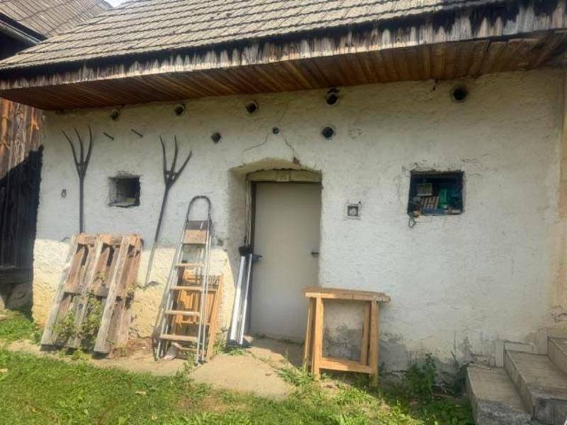 Rustikales Nebengebäude mit alter Fassade und Holzpaletten davor.