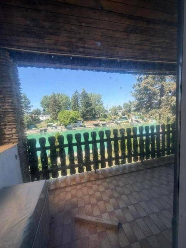 Überdachte Loggia mit Holzbalken und Blick auf den Kanal durch ein rustikales Holzgeländer.