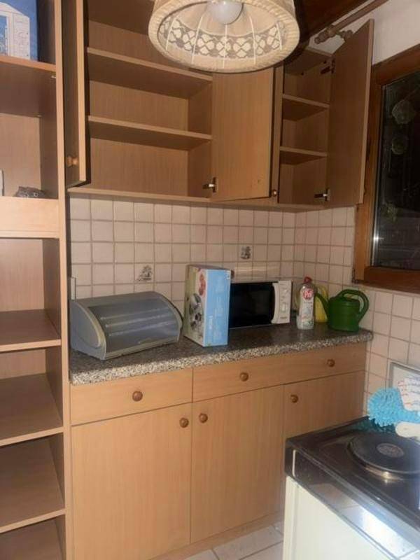 Einfache Küche mit hellbraunen Holzschränken, Granitarbeitsplatte und weißer Fliesenrückwand.