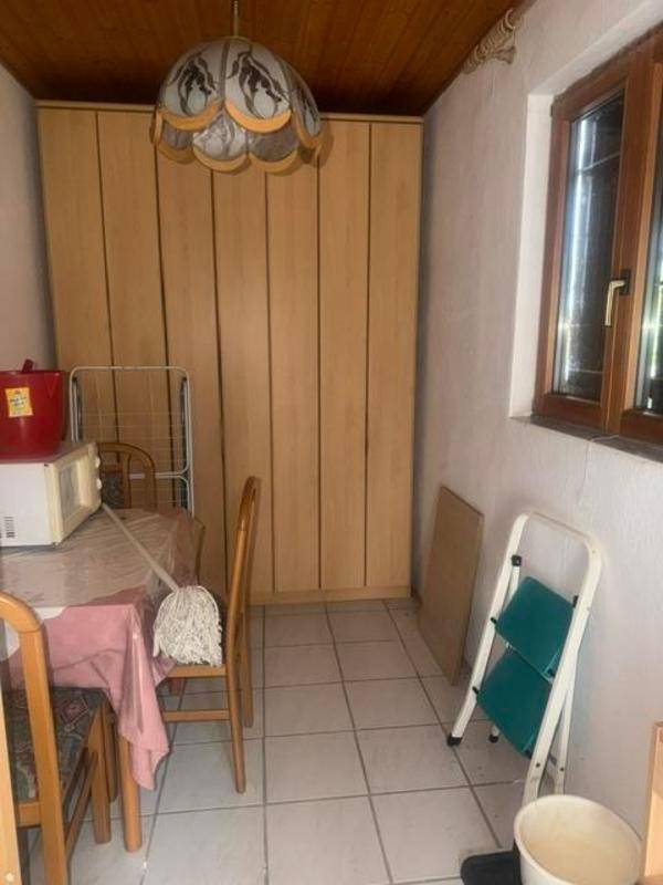 Funktionaler Raum mit großen Holzschränken, Tisch und Fenster, ideal als Abstellraum.