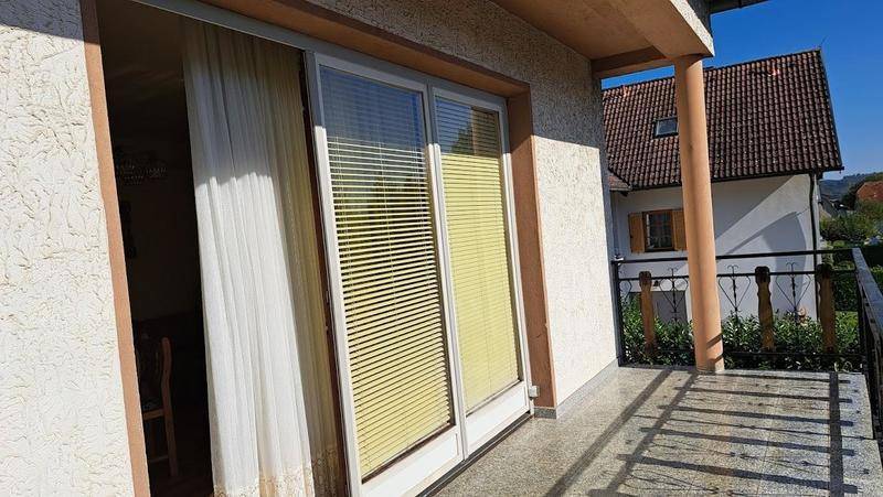 Balkon mit Schiebetür und Jalousien, bietet einen Blick auf die Umgebung.