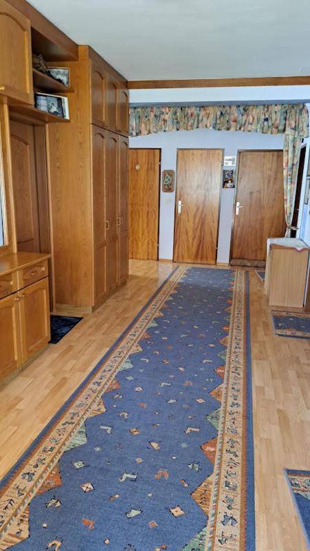 Geräumiger Flur mit Holzschränken, Parkettboden und traditionellem Teppichläufer.
