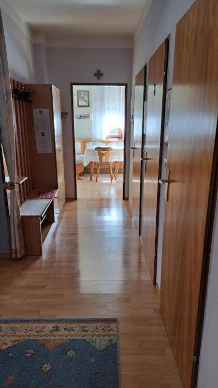 Heller Flur mit Holzfußboden und Garderobe, führt zu weiteren Zimmern.