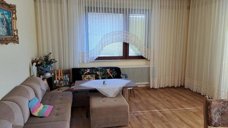 Heller Wohnbereich mit Sofa, Fenster und Vorhängen, bietet viel Tageslicht.