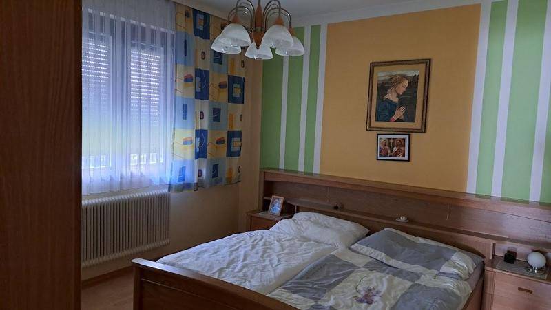 Gemütliches Schlafzimmer mit Doppelbett, Holzmöbeln und farbiger Wandgestaltung für eine wohnliche Atmosphäre.