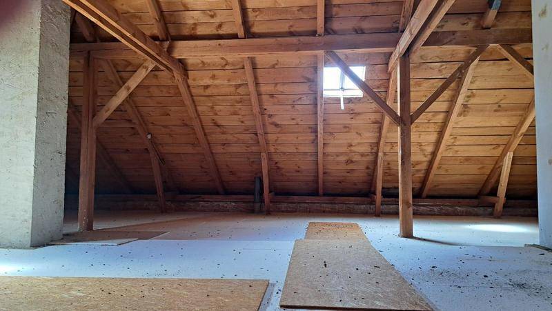 Geräumiger Dachboden mit sichtbaren Holzbalken und einem kleinen Dachfenster, bereit für Ausbau.