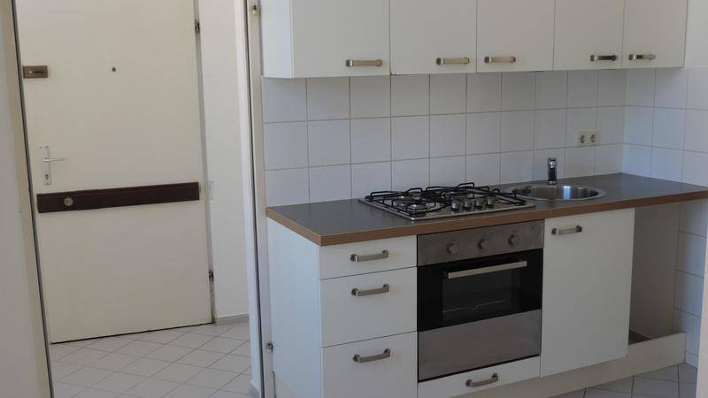 Kompakte Küchenzeile mit Gaskochfeld, Backofen und weißen Hängeschränken.