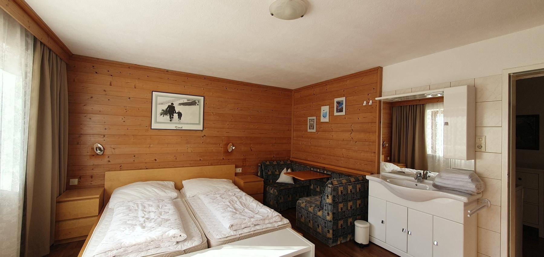 Schlafzimmer mit Doppelbett, Holztäfelung und integriertem Waschbecken.