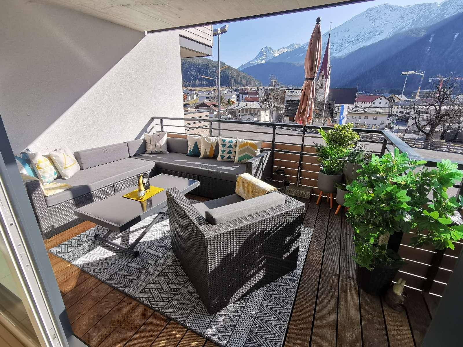 Geräumiger Balkon mit bequemen Loungemöbeln und Panoramablick auf die umliegende Berglandschaft.