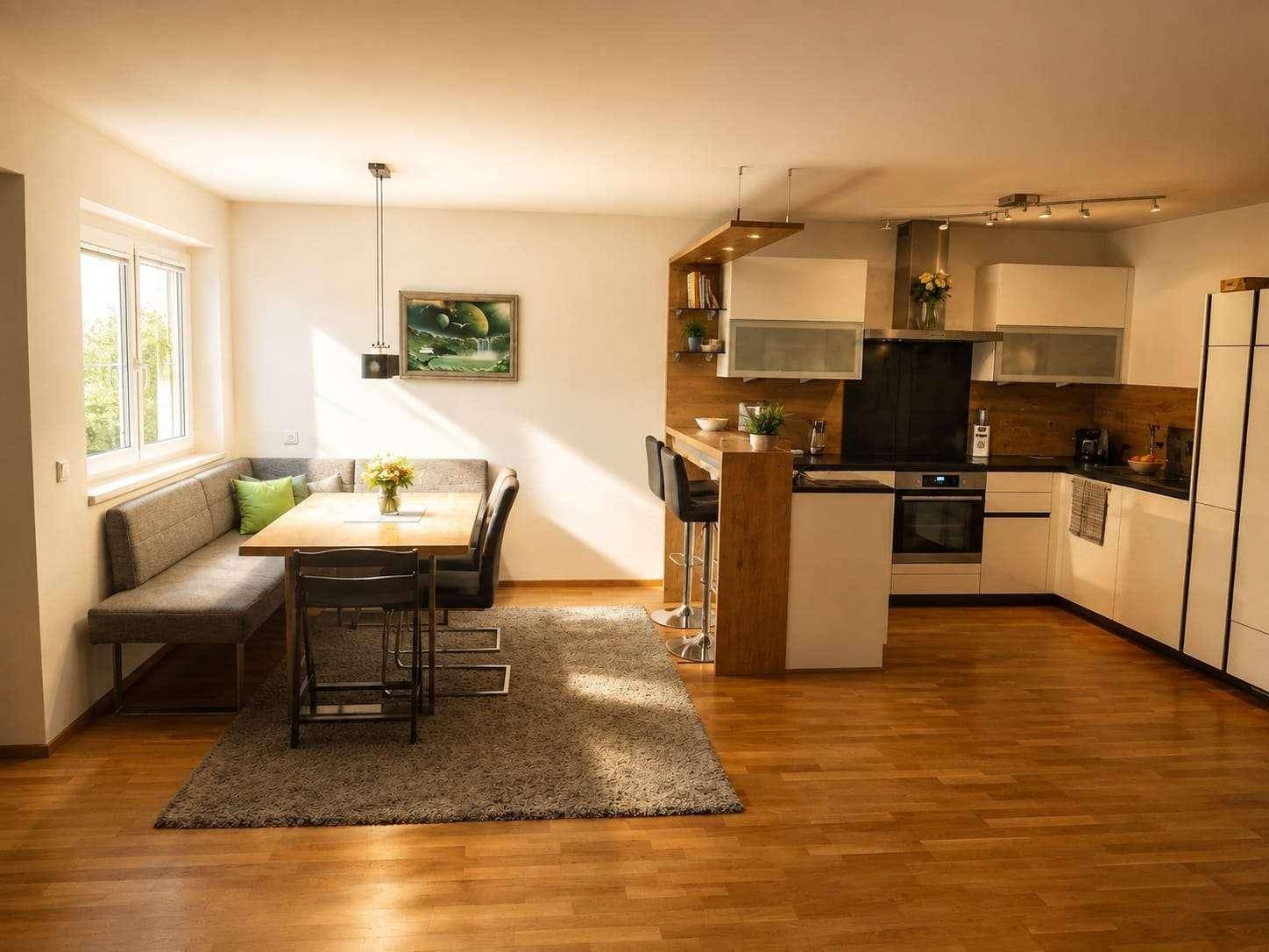 Offener Wohnbereich mit integrierter Küche, Essbereich und Holzboden, ideal für geselliges Beisammensein.