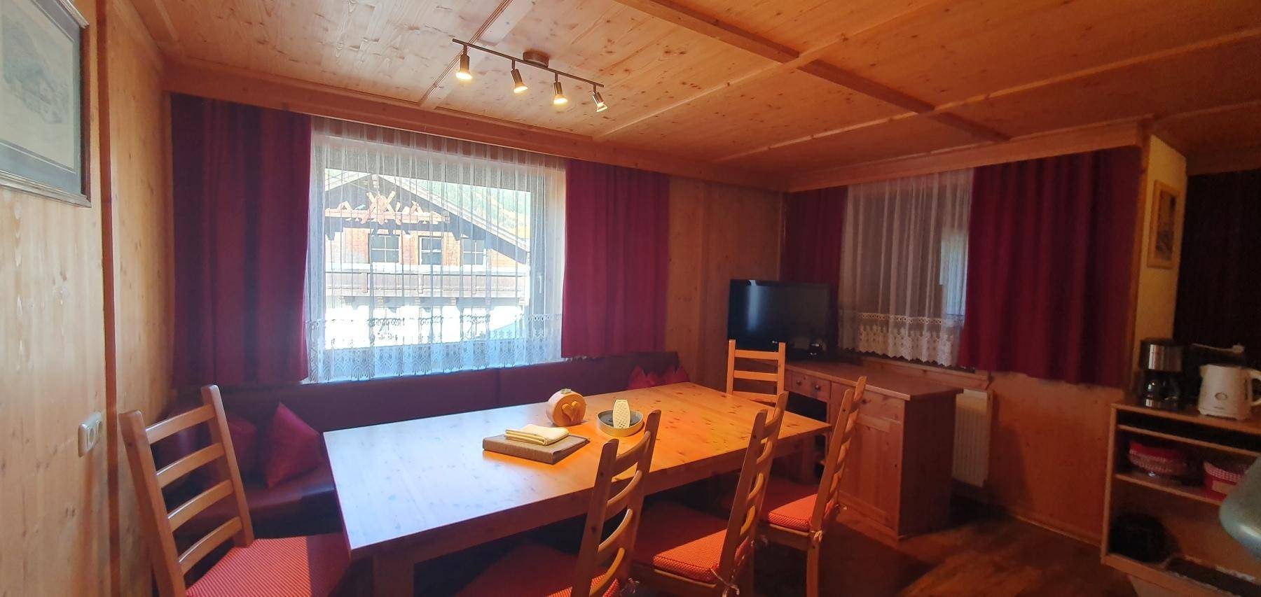 Heller Essbereich mit Holztisch und Blick durch das Fenster auf die Umgebung.