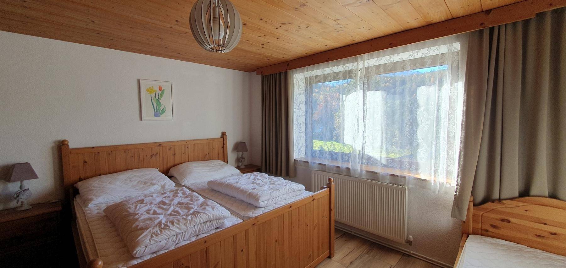 Helles Schlafzimmer mit Holzbetten, Holzboden und großem Fenster.