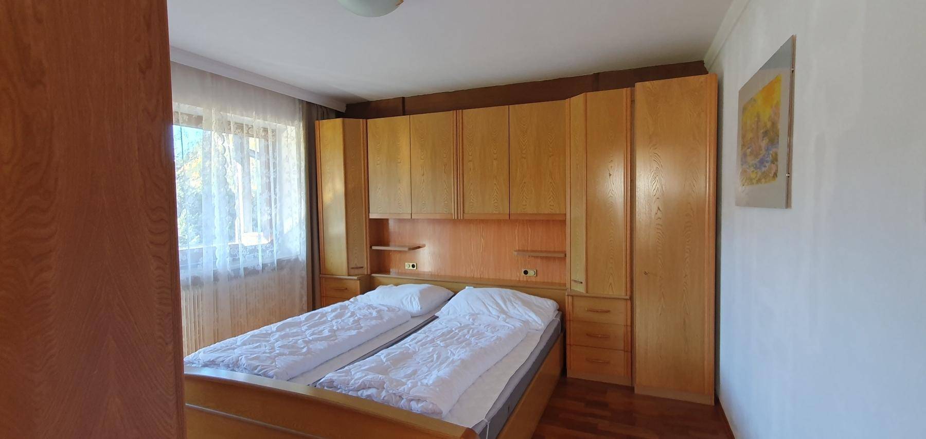 Schlafzimmer mit integrierten Holzschränken und Doppelbett.