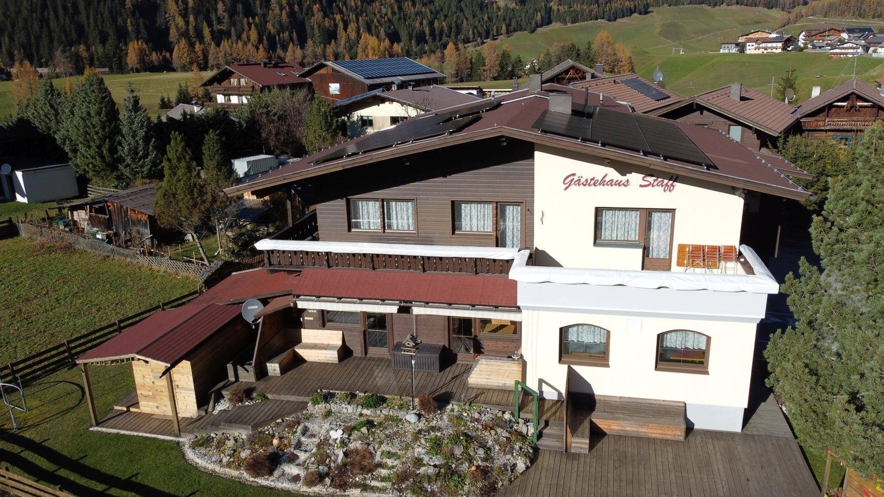 Luftaufnahme des Gasthauses mit Solarpaneelen auf dem Dach und umliegenden Häusern.