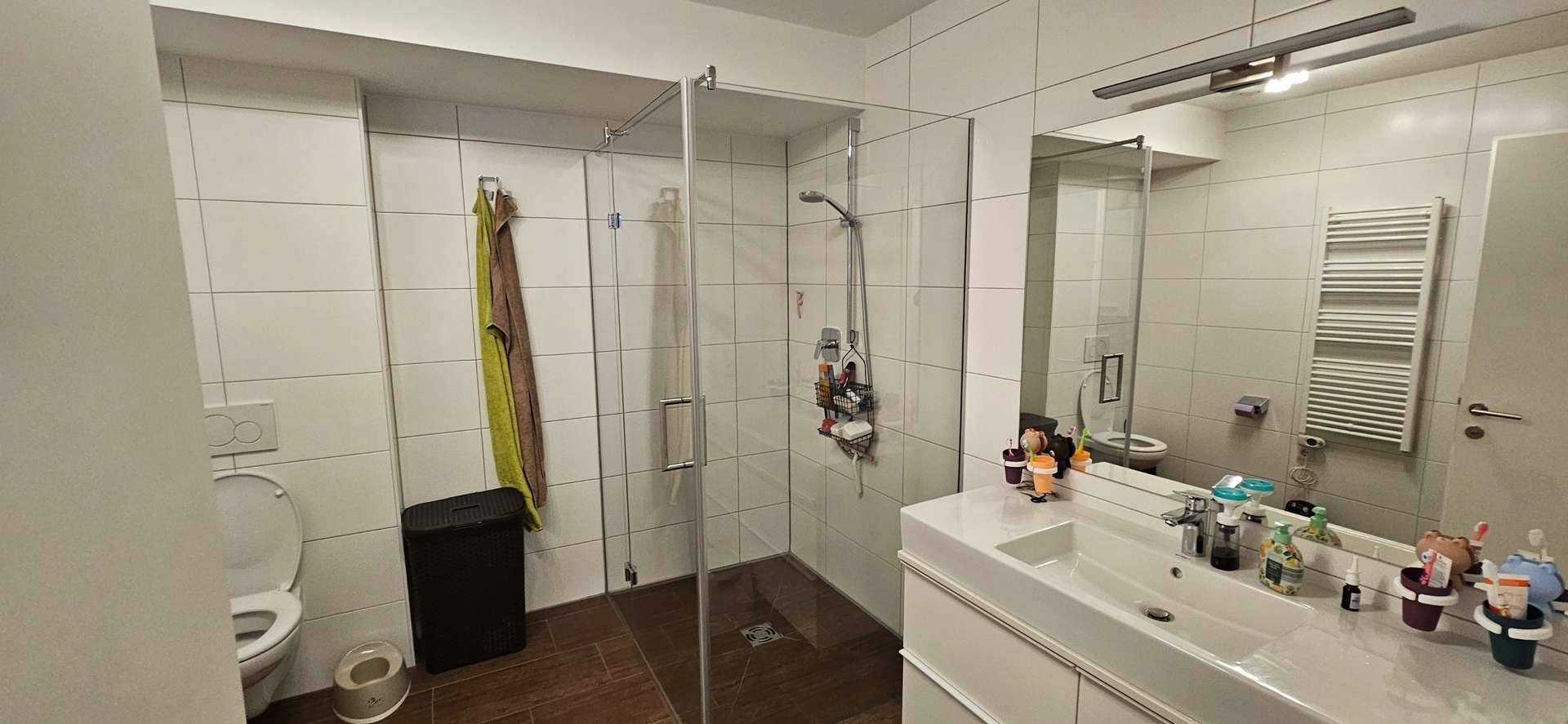 Modernes Badezimmer mit Duschkabine, Einzelwaschbecken und beheiztem Handtuchhalter.