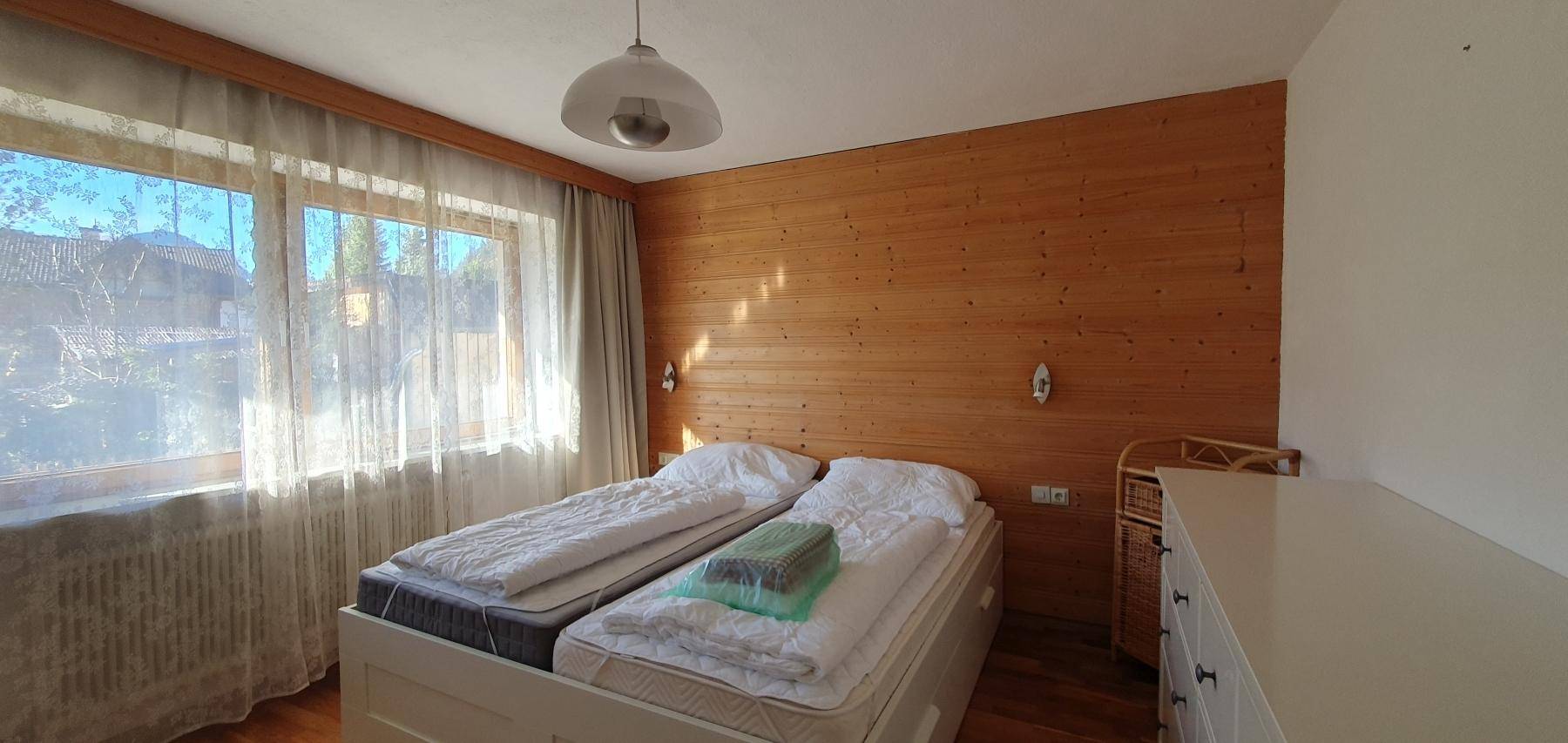 Helles Schlafzimmer mit zwei Einzelbetten und Holzwand.